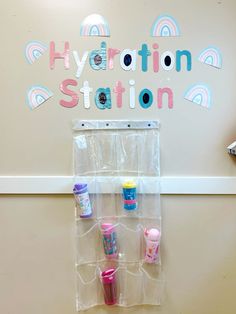 there is a sign that says hydration station with cups and toys on the wall