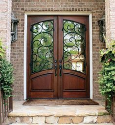 the front door to a brick house with iron work on it's glass panels