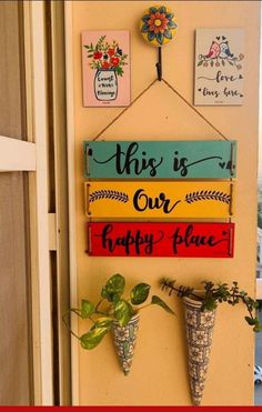 this is our happy place sign hanging on the wall next to potted plants and flowers