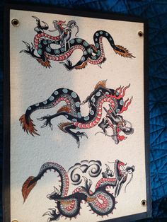 two dragon tattoos on a white paper with black trim and red, blue, and green designs