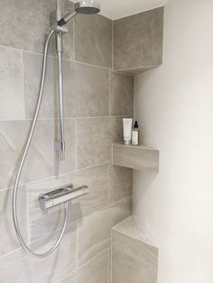 the shower head is mounted on the wall next to the shelf in the shower stall