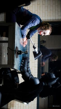 a man in black pants and boots standing next to a mirror