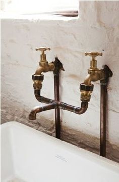 two brass faucets are attached to the wall next to a white bathtub