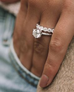 a close up of a person's hand with a diamond ring on their finger