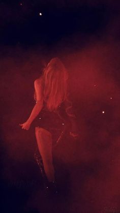 a woman is standing in the dark with her legs spread out and she has long blonde hair