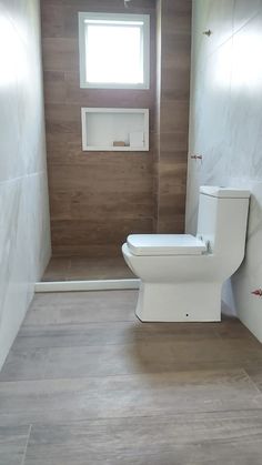 a white toilet sitting in a bathroom next to a window