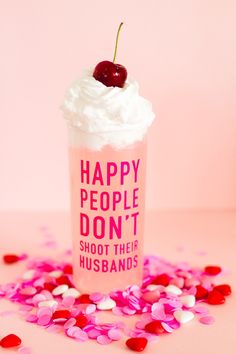 a pink cup with whipped cream and a cherry on top that says happy people don't shoot their husbands