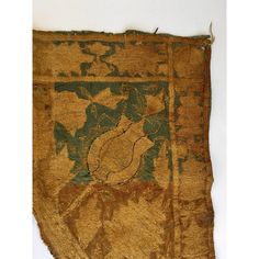 an old piece of cloth with green and brown designs on it, hanging from a wall