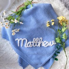 a blue sweater with flowers on it and the word mother spelled in white