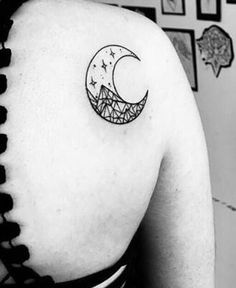 a woman's back shoulder with a crescent and stars tattoo on it