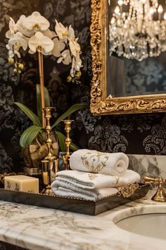 a bathroom sink with towels, candles and a mirror in front of it on top of a marble counter