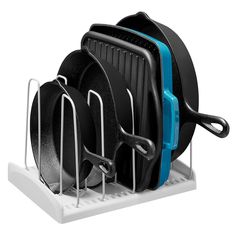 three pots and two pans are in a rack with black plates on it,