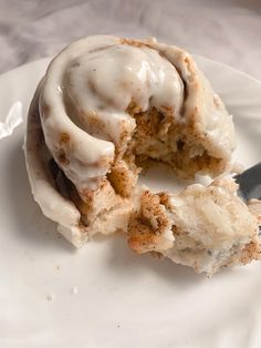 a white plate topped with a donut covered in icing and a bite taken out of it