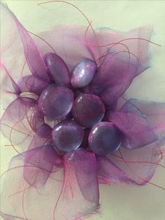 a close up view of some purple flowers on a white table cloth with red thread