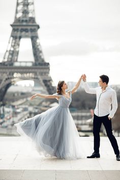 a man and woman dancing in front of the eiffel tower