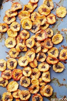 peeled bananas on a baking sheet ready to be cooked in the oven with oil sprinkled over them