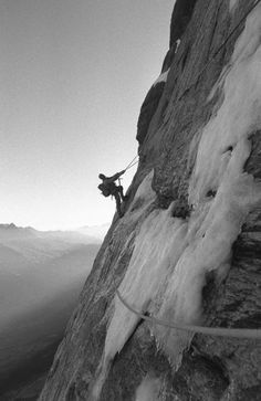 a man climbing up the side of a snow covered mountain