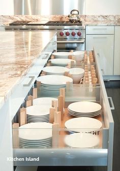 an open drawer in the middle of a kitchen with plates and bowls on it's sides