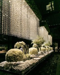 a long table filled with lots of white flowers and vases covered in crystal beads