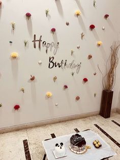 a birthday cake sitting on top of a table in front of a wall with flowers