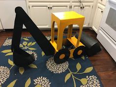 a yellow and black toy truck sitting on top of a blue rug in a kitchen