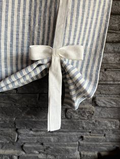 the back of a chair with a bow tied to it's seat cushion, in front of a brick wall