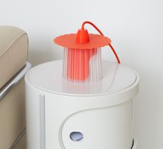 an orange object sitting on top of a white table next to a beige chair and ottoman