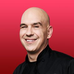 a bald man with a black shirt and red background