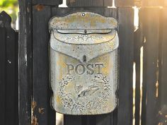 an old mailbox is attached to a wooden fence with the word post painted on it