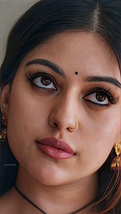 a close up of a woman with big eyes and gold jewelry on her neck looking at the camera