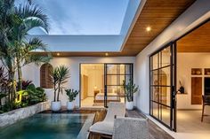 an indoor swimming pool in the middle of a patio area with chairs and potted plants