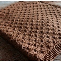 a brown knitted blanket sitting on top of a wooden table