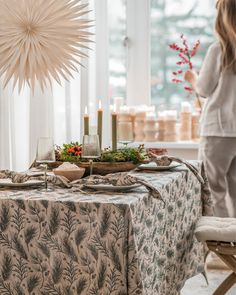 a woman standing in front of a table with food on it and candles lit up