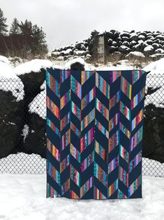 a quilt is hanging on a fence in the snow