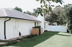 a white house sitting next to a lush green field on top of a grass covered yard