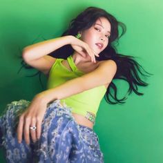 a woman posing in front of a green wall