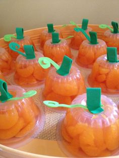 small plastic pumpkins are sitting on a tray with green paper clips stuck to them