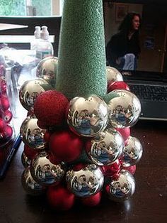 a christmas tree made out of balls on a desk next to a laptop and other decorations