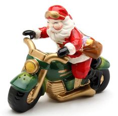 a santa clause riding on the back of a motorbike ornament in gold, green and red