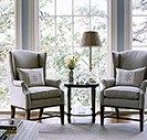 a living room with two chairs and a coffee table in front of a large window