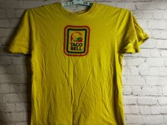 Vintage Style Tan Cotton Tops, Retro Tan Crew Neck Top, Vintage Tan Short Sleeve Tops, 90s Style Yellow Crew Neck T-shirt, Tan Crew Neck Top, Pre-shrunk Tan Crew Neck Top, Taco Bell Logo, Bell Logo, Taco Bell