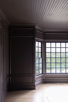 an empty room with wood paneling and large windows