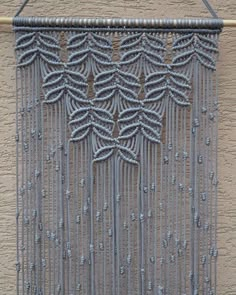 a close up of a metal object on a wall with beads hanging from it's sides