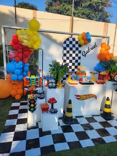 a checkered table with balloons and other decorations on it in front of a fence