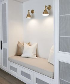 a white room with two lamps on the wall and a bench in front of it