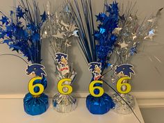 three vases with blue and silver decorations on top of a white table in front of a wall