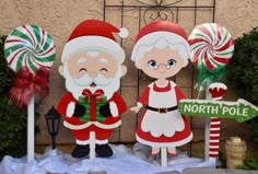 christmas decorations with santa and mrs claus on display in front of a building that says north pole