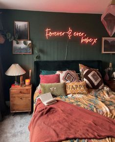 a bed room with a neatly made bed and a neon sign above it