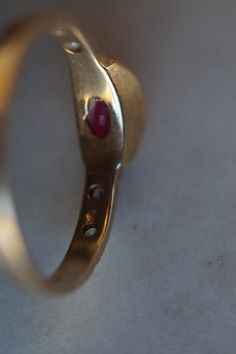 A modern deceptively lovely ruby ring 10K gold smooth bezel set oval ruby stone flanked by tiny diamonds Illegible mark Size 8.5 Vintage Ruby Ring With Bezel Setting, Vintage 14k Gold Ruby Ring With Bezel Setting, Antique Oval Ruby Promise Ring, Oval Ruby Ring Stamped 14k, Vintage Oval Ruby Ring With Bezel Setting, Oval Ruby Ring With 17 Jewels For Promise, Oval Ruby Promise Ring With 17 Jewels, Classic Oval Cabochon Ruby Promise Ring, Gold Ruby Ring