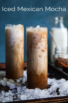 two tall glasses filled with ice on top of a tray next to salt and pepper shakers